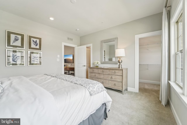 bedroom with a closet, visible vents, light carpet, baseboards, and a spacious closet