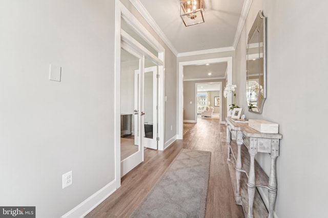 corridor with ornamental molding, wood finished floors, french doors, and baseboards