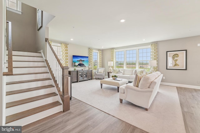 living area with baseboards, stairway, a wealth of natural light, and light wood-style floors