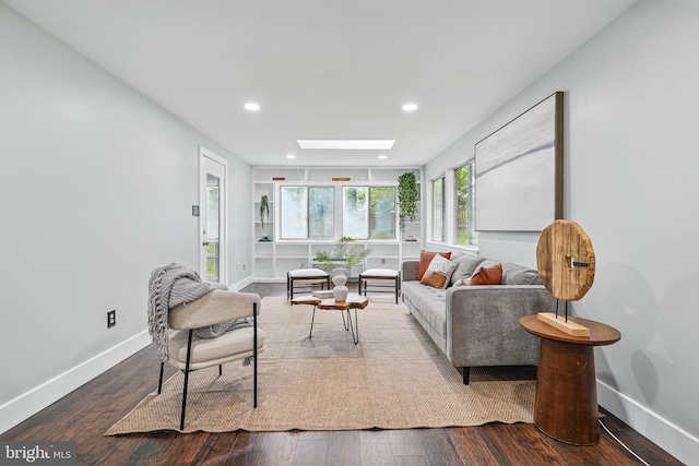 living area featuring a skylight, baseboards, recessed lighting, and wood finished floors