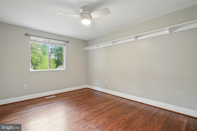 empty room with baseboards, ceiling fan, wood finished floors, and visible vents