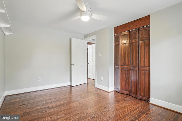 unfurnished bedroom with a closet, dark wood finished floors, ceiling fan, and baseboards