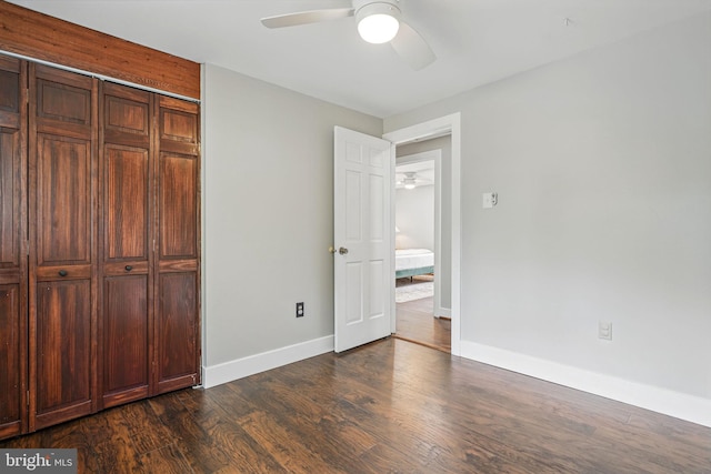 unfurnished bedroom featuring baseboards, dark wood finished floors, ceiling fan, and a closet