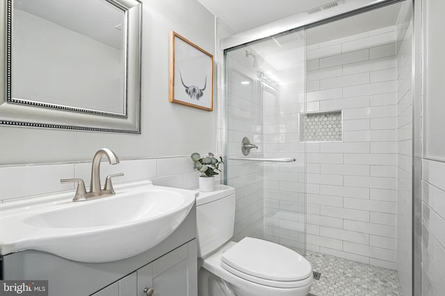 full bath featuring toilet, tile walls, tiled shower, and vanity