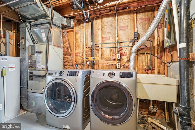 clothes washing area featuring water heater, laundry area, independent washer and dryer, and a sink