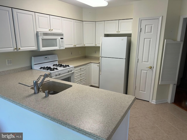 kitchen with a sink, white appliances, white cabinetry, a peninsula, and light tile patterned floors