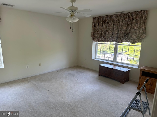 interior space with visible vents, baseboards, ceiling fan, and light carpet