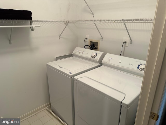 washroom featuring laundry area, baseboards, washing machine and dryer, and light tile patterned flooring
