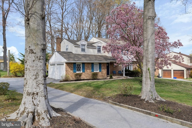 view of front of house with brick siding, driveway, a chimney, and a front lawn