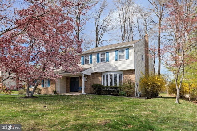 view of front facade with a chimney, a front lawn, and brick siding