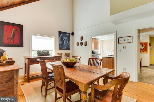 dining space featuring light wood-type flooring and high vaulted ceiling
