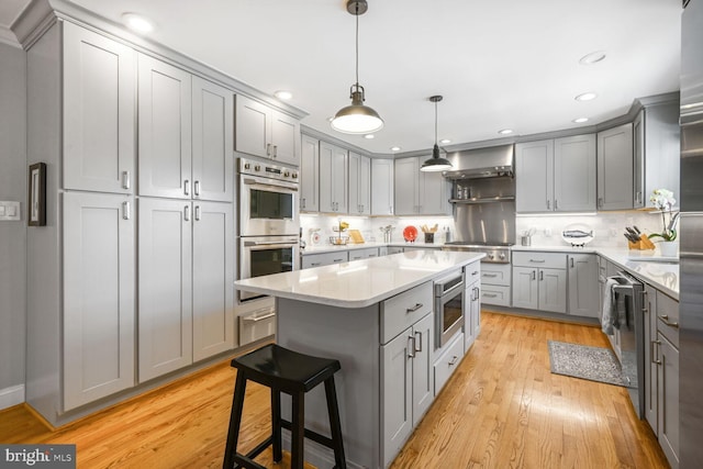 kitchen with a center island, gray cabinets, appliances with stainless steel finishes, and light wood finished floors