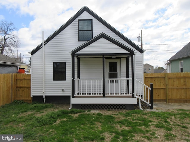 view of front of house featuring a front yard, a porch, and a fenced backyard