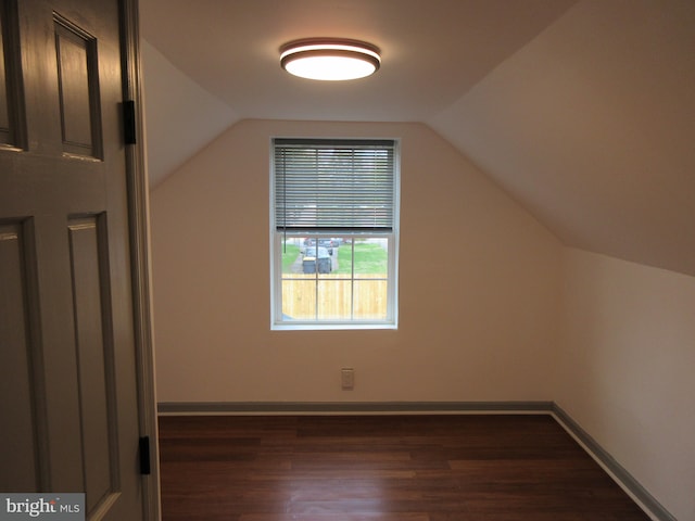 additional living space with lofted ceiling, baseboards, and dark wood finished floors