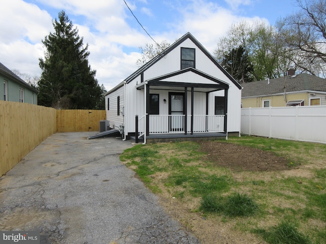 bungalow with a porch, a fenced backyard, and central AC