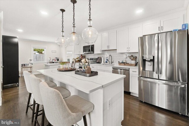 kitchen featuring appliances with stainless steel finishes, white cabinets, a center island, and dark wood-type flooring