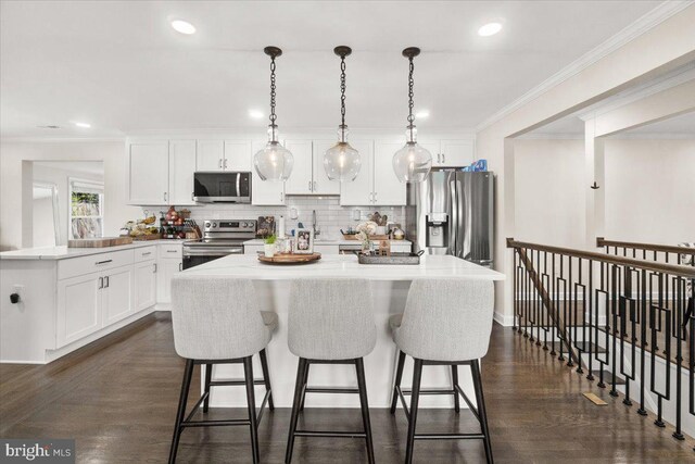 kitchen featuring white cabinetry, appliances with stainless steel finishes, backsplash, and a breakfast bar area