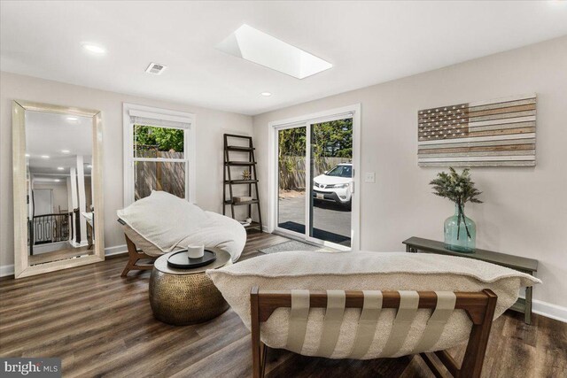 living area with a skylight, visible vents, a wealth of natural light, and dark wood-type flooring