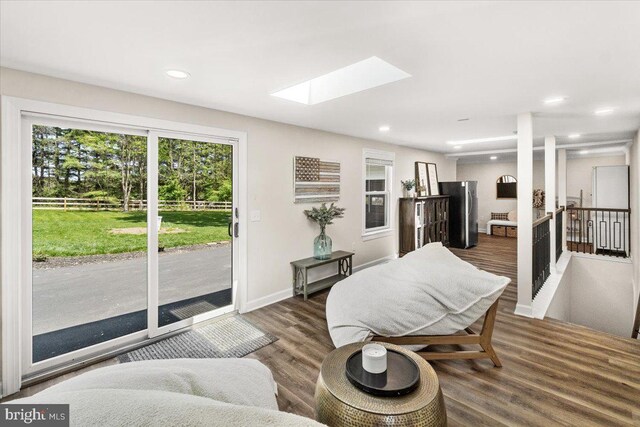 sitting room with a skylight, baseboards, recessed lighting, and wood finished floors