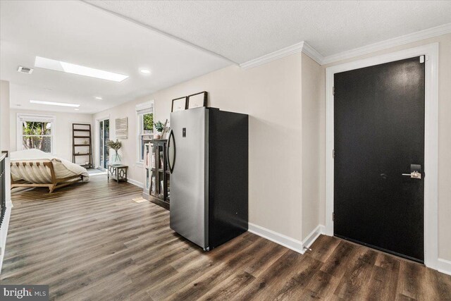kitchen featuring visible vents, freestanding refrigerator, dark wood-style flooring, crown molding, and baseboards