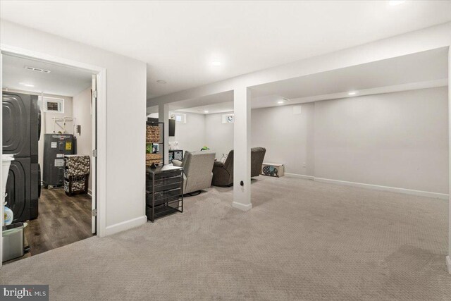 finished basement featuring visible vents, baseboards, recessed lighting, electric water heater, and carpet