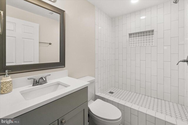full bathroom featuring vanity, toilet, and tiled shower