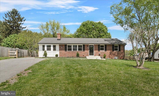 single story home with fence, brick siding, a front yard, a chimney, and driveway