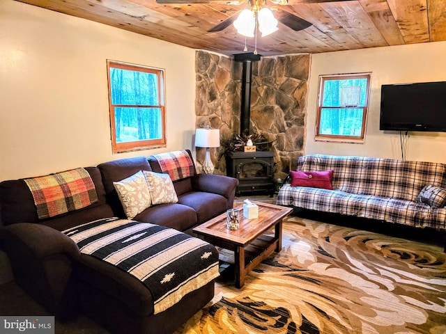 living room featuring a wood stove, wood ceiling, and ceiling fan