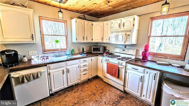 kitchen with a sink, dark countertops, wood ceiling, and white appliances