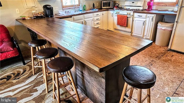 kitchen featuring a peninsula, a breakfast bar area, a toaster, and white appliances