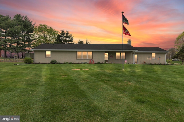 view of front of home featuring brick siding, a front yard, and a chimney