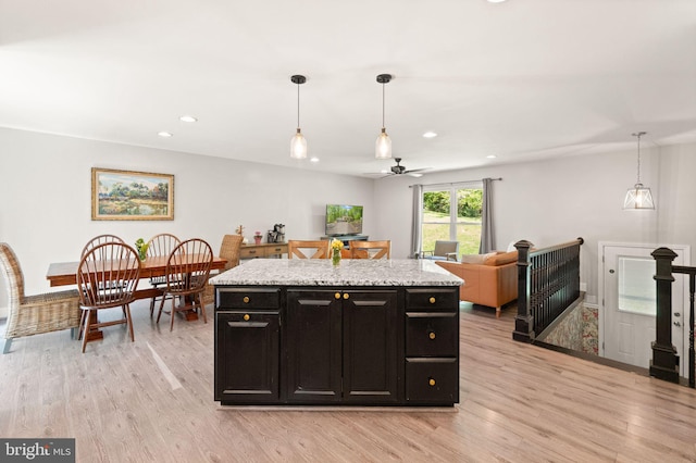 kitchen featuring light wood-type flooring, pendant lighting, a ceiling fan, and dark cabinets