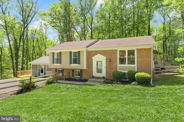 raised ranch with fence, a front lawn, a chimney, and brick siding