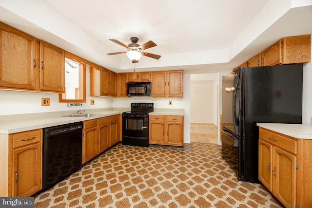 kitchen featuring brown cabinets, a sink, light countertops, black appliances, and a ceiling fan