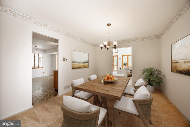 dining area with light colored carpet, visible vents, a notable chandelier, and baseboards