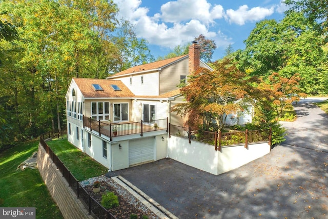 back of property featuring fence, aphalt driveway, and an attached garage