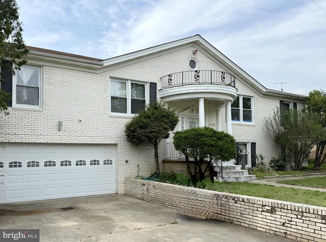 neoclassical home with concrete driveway, an attached garage, brick siding, and a balcony