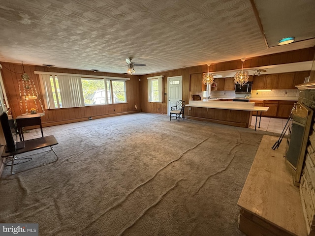 living area with wood walls, a ceiling fan, and light carpet