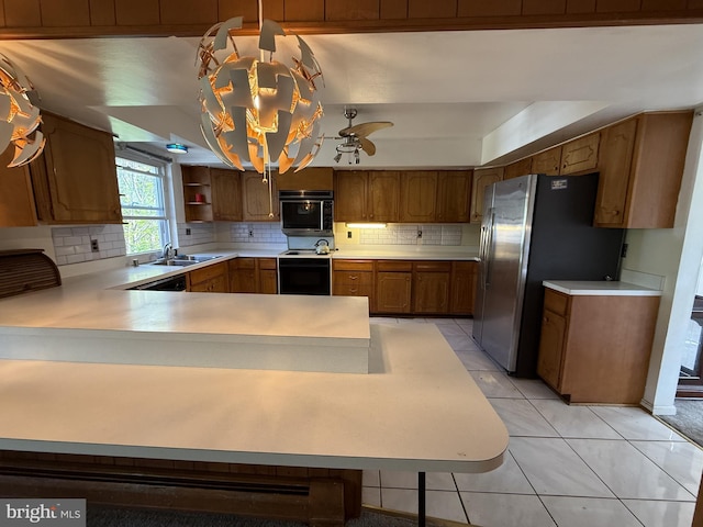 kitchen featuring a sink, decorative backsplash, range with electric stovetop, light countertops, and freestanding refrigerator