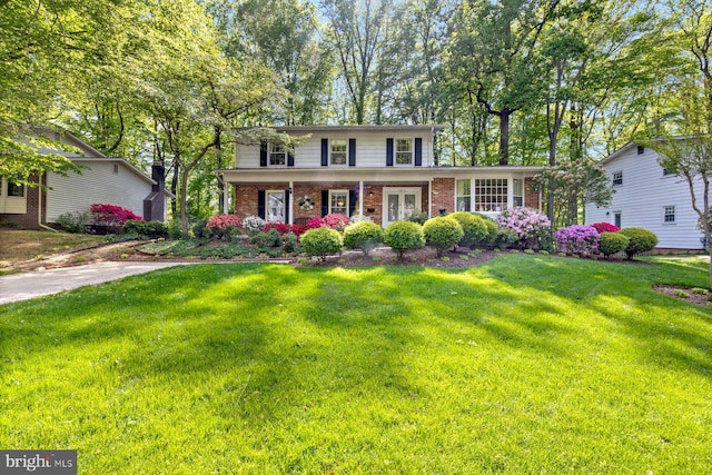 traditional-style house featuring brick siding, covered porch, and a front yard