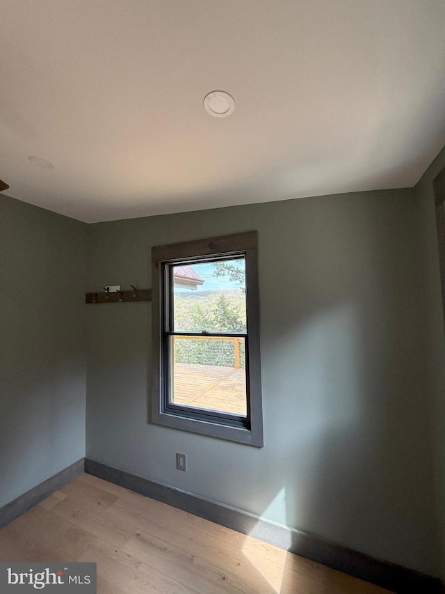 unfurnished room with baseboards and light wood-style floors