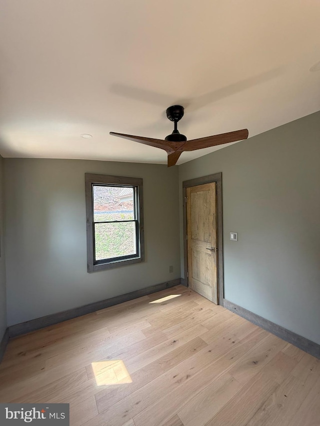 spare room featuring ceiling fan, light wood-style flooring, and baseboards
