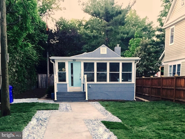 view of front of house with a chimney, fence, entry steps, and a front lawn