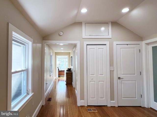 hallway with visible vents, wood finished floors, and lofted ceiling