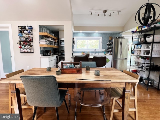 dining room with wood finished floors, rail lighting, and lofted ceiling