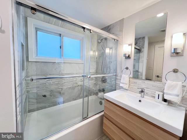 bathroom featuring vanity, combined bath / shower with glass door, and decorative backsplash