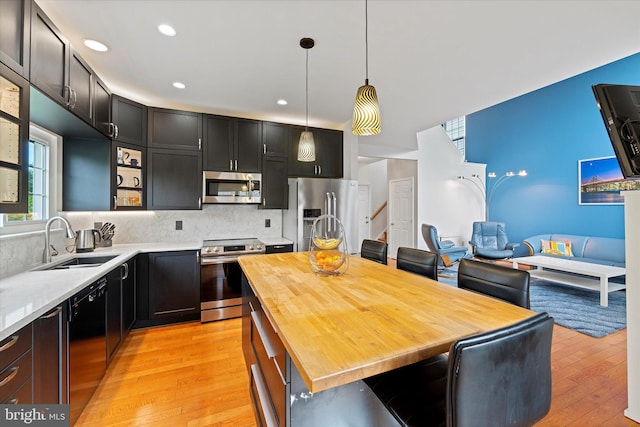 6780 Hollow Glen Ct, Gainesville, VA 20155 - kitchen featuring appliances with stainless steel finishes, a sink, light wood-style floors, hanging light fixtures, and tasteful backsplash