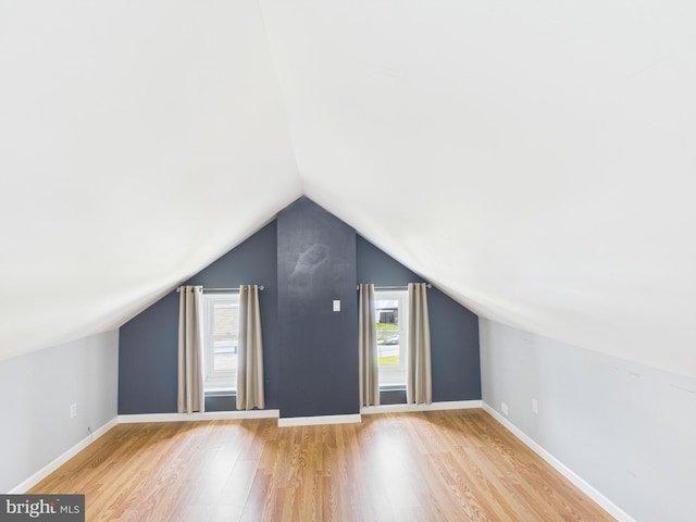 additional living space with wood finished floors, lofted ceiling, and baseboards