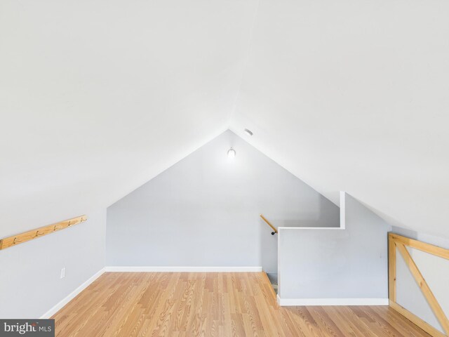 bonus room featuring vaulted ceiling, baseboards, and wood finished floors
