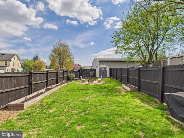 view of yard with a fenced backyard, a garden, an outbuilding, an outdoor fire pit, and a storage unit